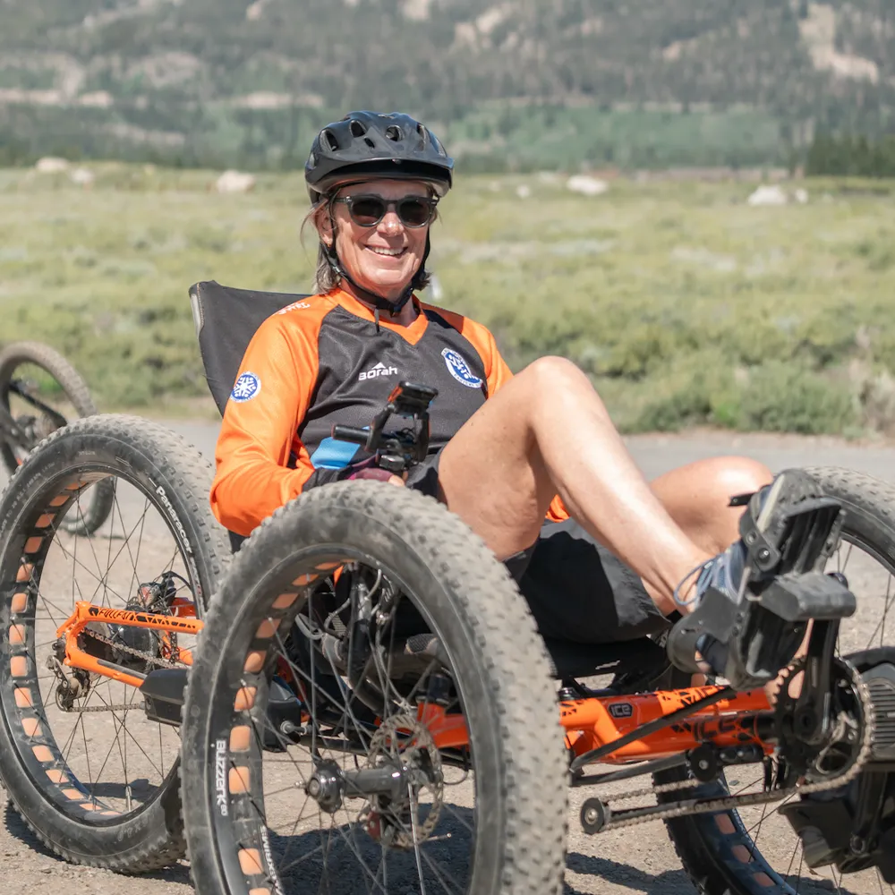 About Us page photo featuring Access Mammoth participant smiling on an adaptive road bike