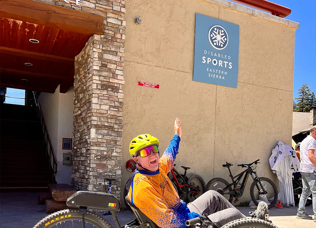 Access Mammoth adaptive athlete pointing to a mammoth mountain sign
