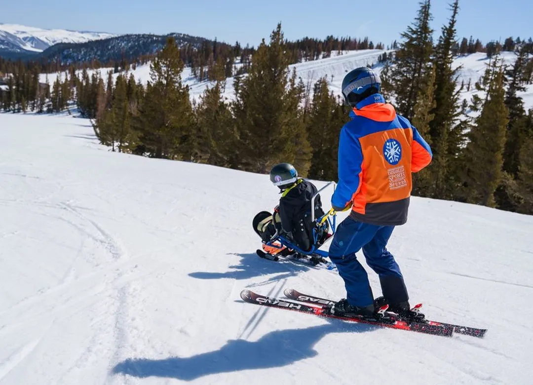 Access Mammoth ski instructor helping an adaptive athlete on a mono ski down mammoth mountain